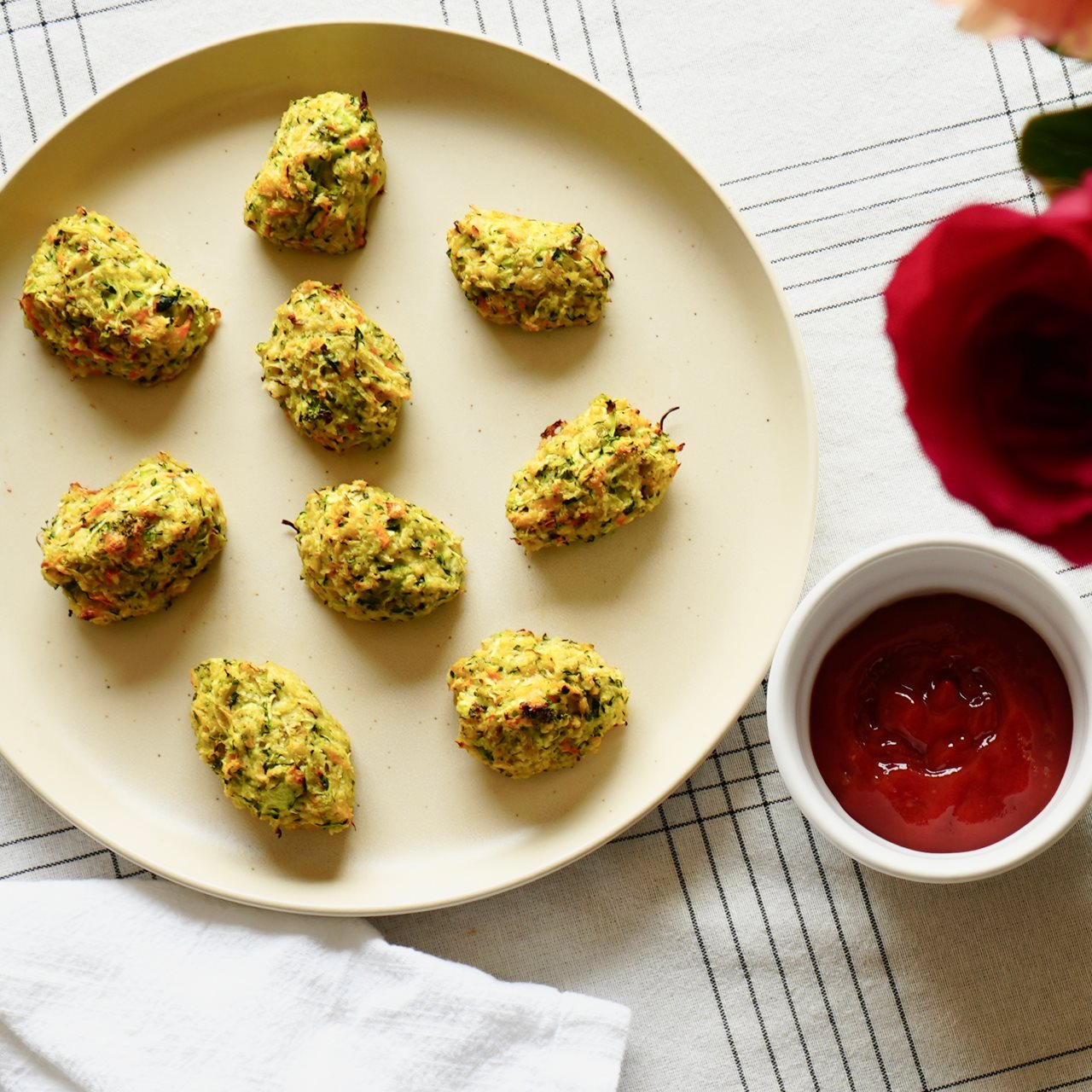 A plate of Zuchini tots with a side of ketchup.