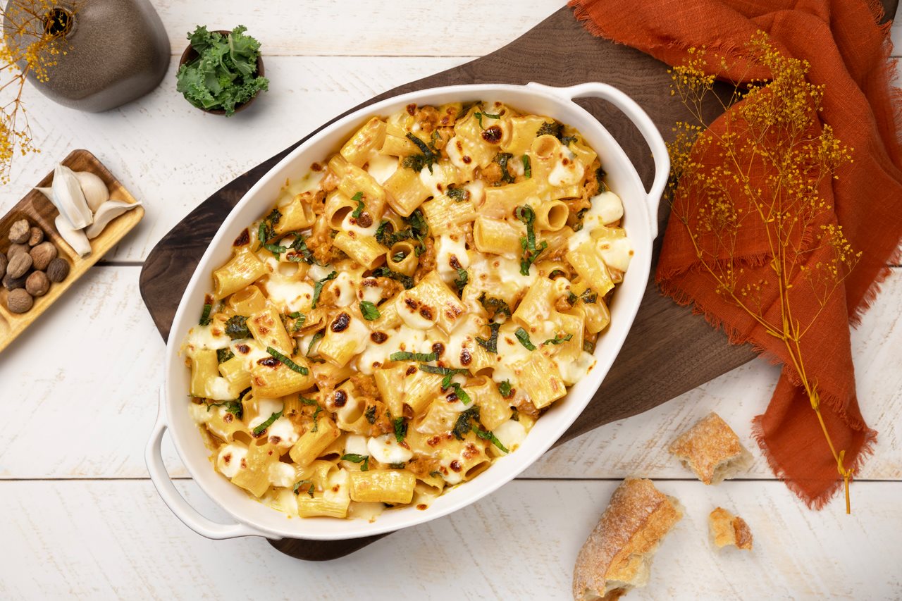 Pumpkin pasta in a cassorole dish on a bread board.