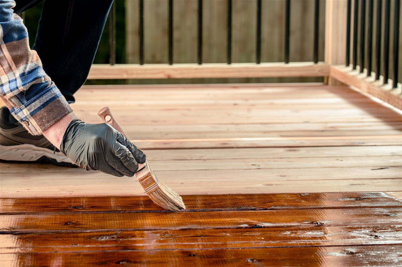 Man sealing a deck with a brush.