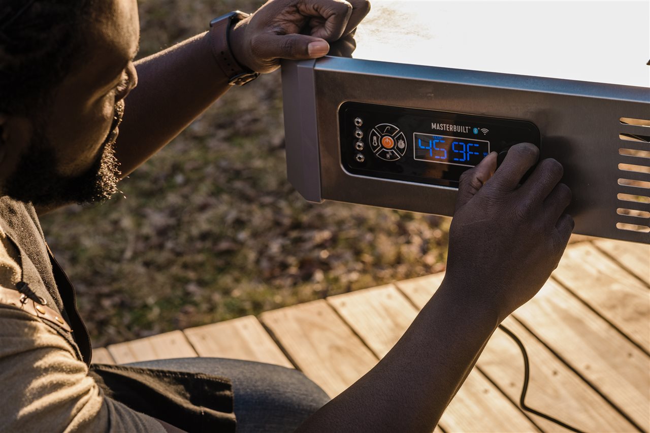 Man setting the temperature on a Grillmaster grill.